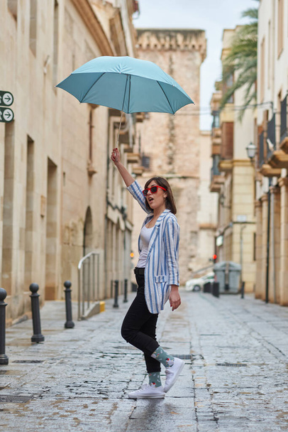 Woman walking down the street on a rainy day with umbrella - 写真・画像