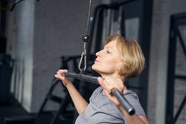 Woman doing exercise with strength trainer in gym - Foto, Bild