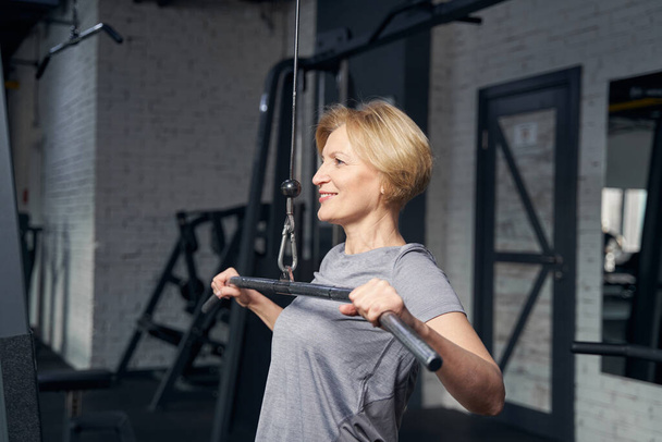 Cheerful woman working out in fitness center - Photo, image