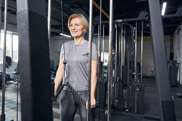 Joyful woman using gym equipment during training - Foto, Imagen