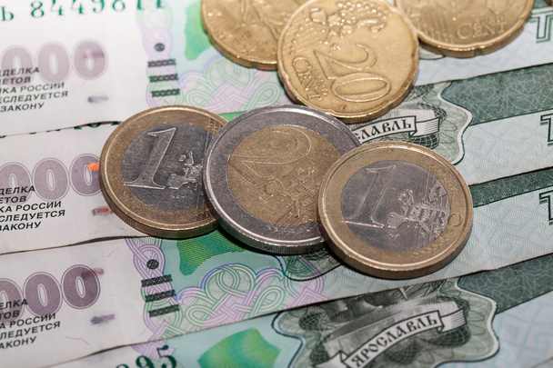Monedas en euros sobre un fondo de mil rublos billetes
 - Foto, imagen