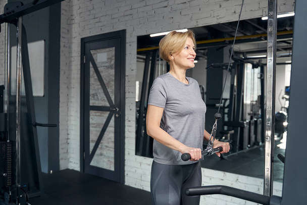 Cheerful woman using gym trainer during strength workout - Foto, immagini