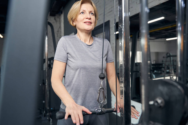 Sporty woman using gym equipment during strength workout - Fotó, kép