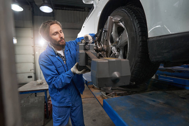 Worker performing car maintenance at service station - Foto, afbeelding