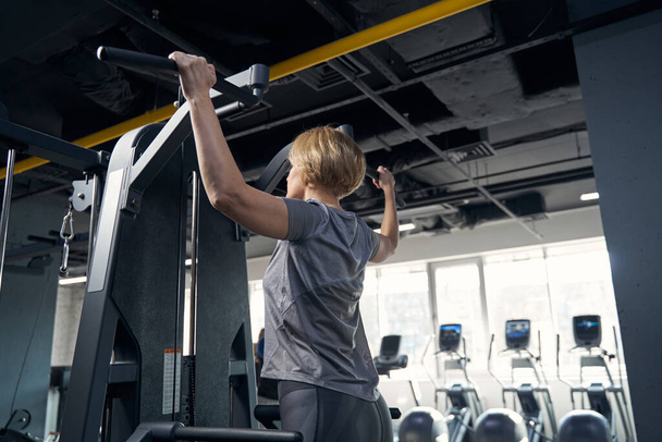 Woman having workout with gym equipment in fitness center - Zdjęcie, obraz
