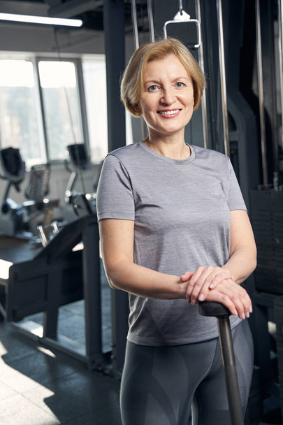 Cheerful woman in sportswear standing in fitness center - Fotoğraf, Görsel
