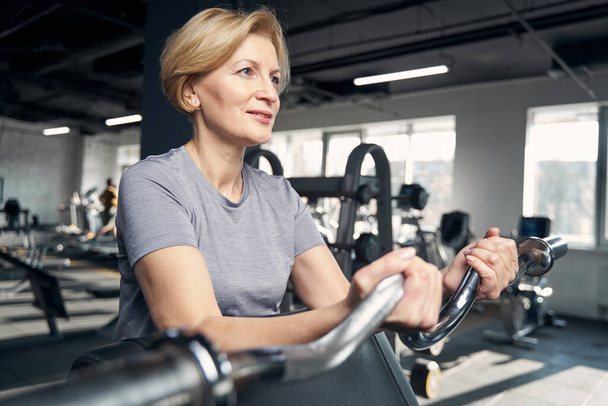 Blonde woman doing exercise with gym equipment - Foto, afbeelding