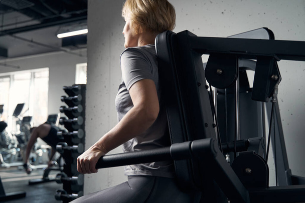 Sporty woman using gym equipment in fitness center - Foto, Imagen