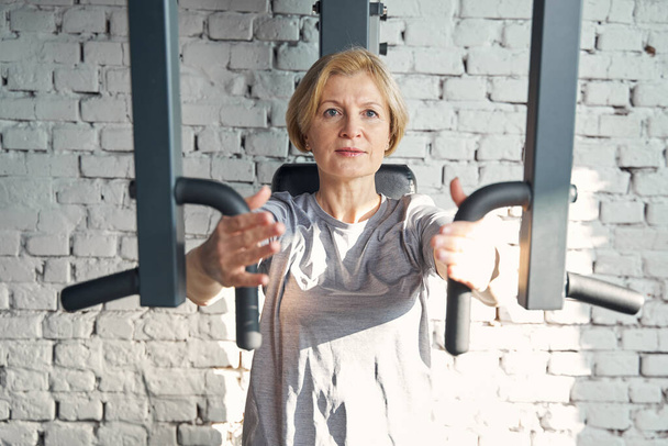 Woman doing exercise with gym trainer against brick wall - Foto, imagen