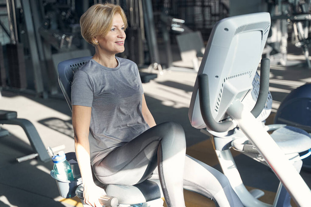 Joyful woman using fitness equipment in gym - Foto, Imagen