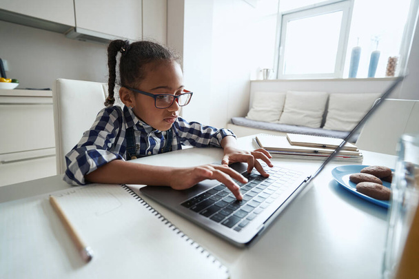 Kleines Mädchen konzentriert sich auf die Tastatur am Laptop - Foto, Bild