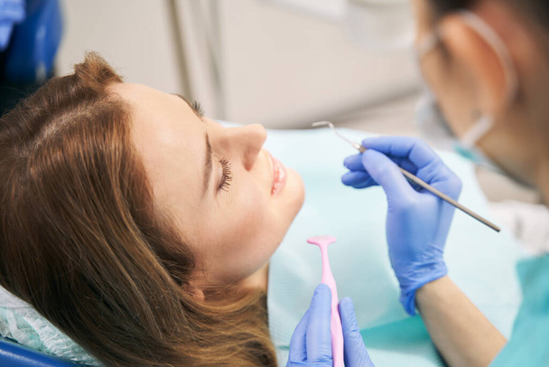 Doctor hands examining woman teeth with dental tools - Фото, изображение