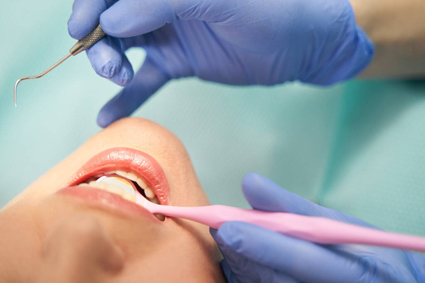 Dentist examining woman teeth with dental mirror and explorer - Foto, imagen