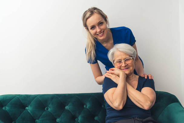 Senior European woman on a sofa holding her caregivers hand. Patient doctor relationship. - Fotó, kép