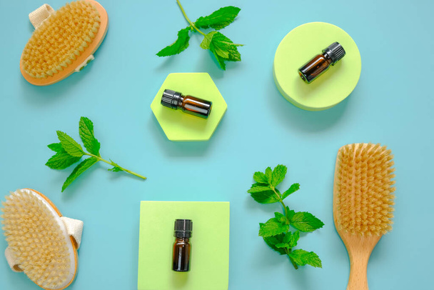 Peppermint essential oil.bottle and body brushes with natural bristles on green podiums against a blue background .Natural Organic Peppermint Oil  - Photo, Image