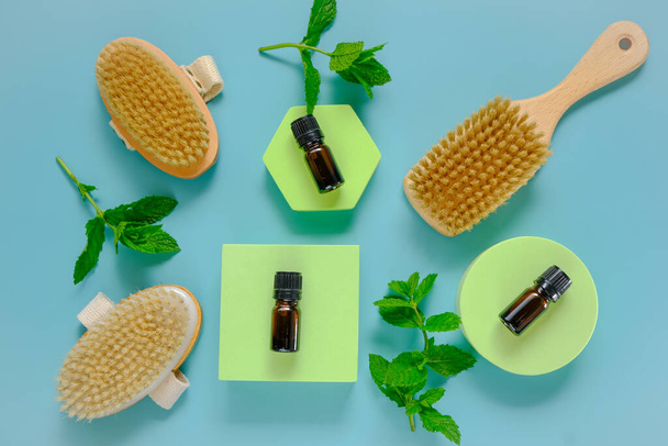 Peppermint essential oil. bottle and body brushes with natural bristles on green podiums - Photo, Image