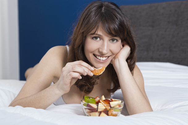 Girl on bed eating fruits - Fotografie, Obrázek