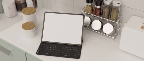 Tableta digital portátil con teclado inalámbrico maqueta de pantalla blanca en la encimera de cocina blanca moderna. Espacio de cocina casera moderna. representación 3d, ilustración 3d - Foto, Imagen