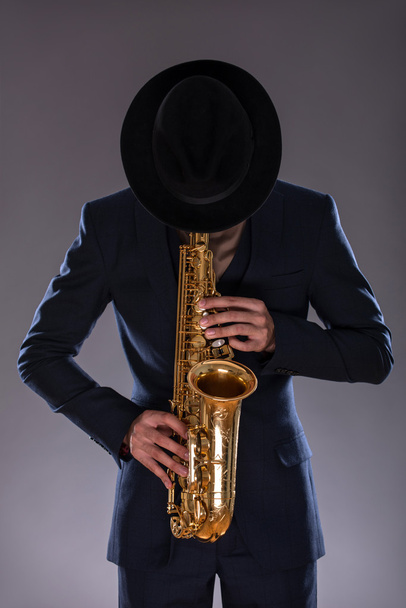 Portrait of a jazz man in a suit with a hat hiding his face and - Φωτογραφία, εικόνα