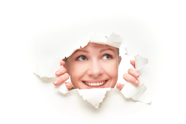 Gesicht einer Frau, die durch ein Loch in ein weißes Papierposter blickt - Foto, Bild