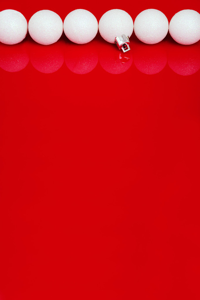Bolas de Navidad blancas en fila sobre el fondo rojo vertical
 - Foto, Imagen