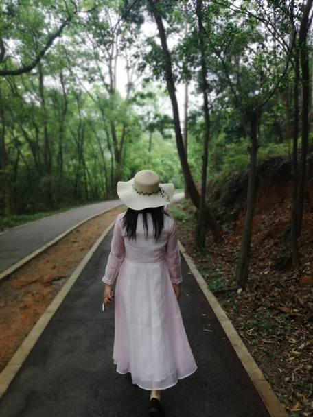 young woman in a hat and a backpack walking in the park - Fotó, kép