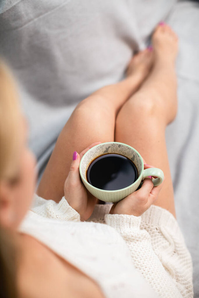 A woman with shapely legs holds a cup of coffee. - Photo, Image