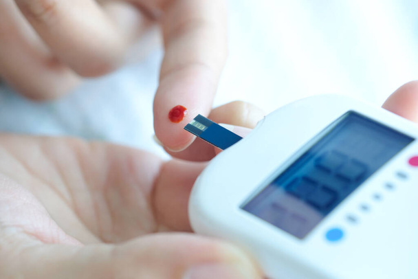 ręka ludzi sprawdzić cukrzycę i wysoki poziom glukozy we krwi z cyfrowym ciśnieniomierzem. Koncepcja opieki zdrowotnej i medycyny - Zdjęcie, obraz