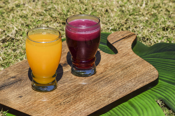 Pomegranate juice and Orange juice malta juice in transparent glass on grass background. Anaar juice santra ras on wooden board - Foto, imagen
