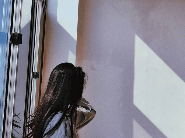 young woman in a black dress with a window - Zdjęcie, obraz