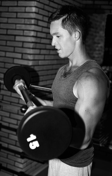 Mann trainiert im Fitnessstudio mit Langhantel - Foto, Bild