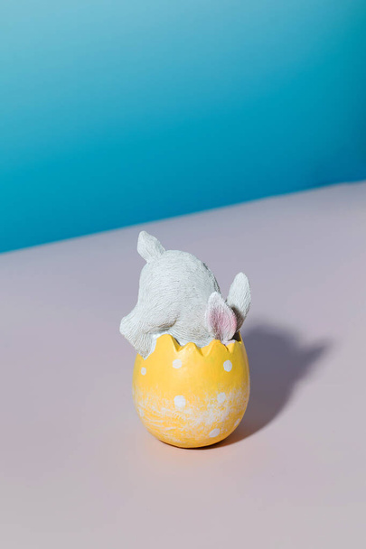 A white rabbit in an Easter egg on a blue background. The concept of a happy Easter. - Fotografie, Obrázek
