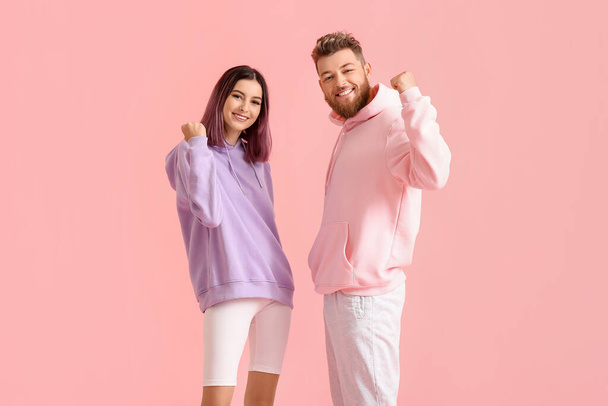 Cool jeune couple heureux en sweats à capuche sur fond de couleur - Photo, image