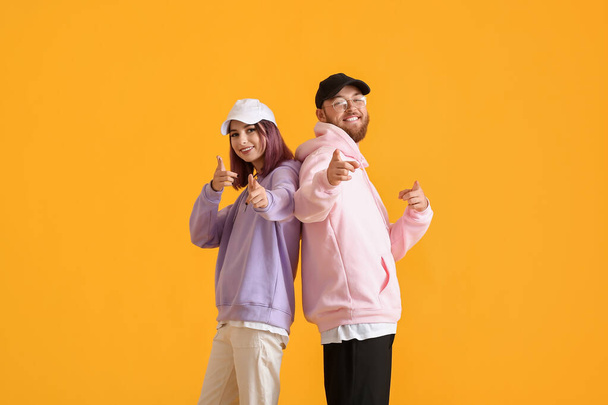 Cool jong paar in hoodies op kleur achtergrond - Foto, afbeelding