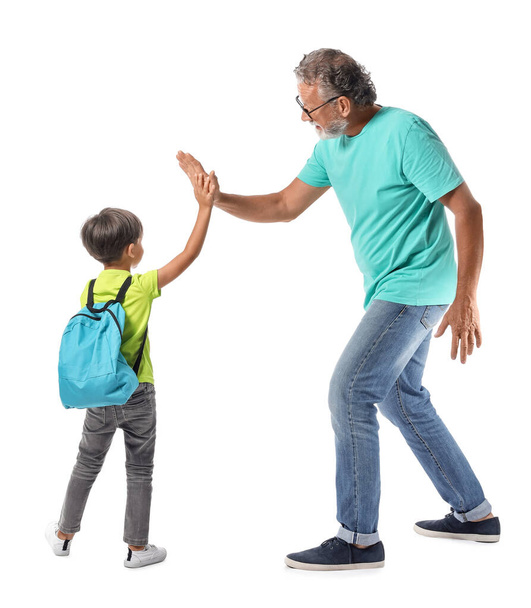 Petit écolier avec sac à dos donnant high-five à son grand-père sur fond blanc - Photo, image
