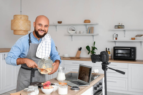 Hombre guapo preparando magdalenas de melocotón y grabación video tutorial en la cocina - Foto, imagen