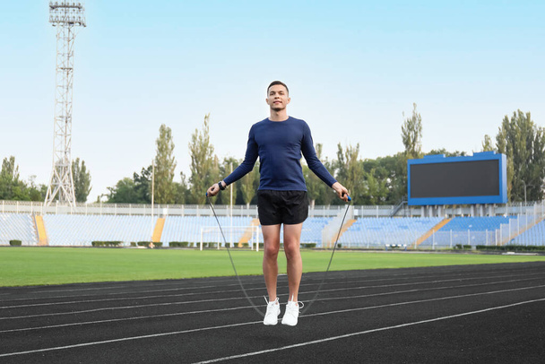 Sporty young man skipping rope at stadium - Photo, Image