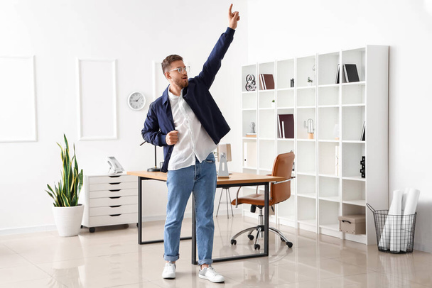 Красивый молодой бизнесмен танцует в офисе - Фото, изображение