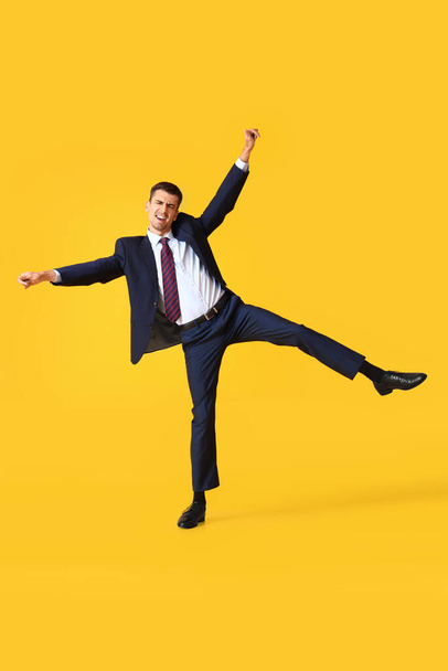 Táncoló fiatal üzletember sárga háttér - Fotó, kép