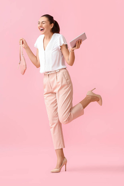 Šťastná mladá podnikatelka s tabletu počítače a taška na růžovém pozadí - Fotografie, Obrázek