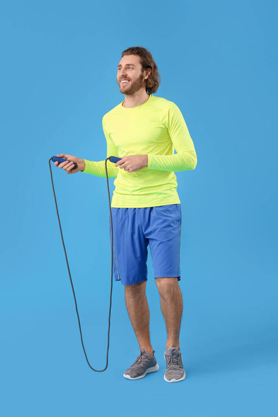 Sporty man with jumping rope on blue background - Photo, Image