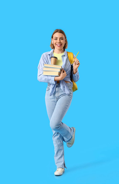 Female student with books on blue background - Zdjęcie, obraz