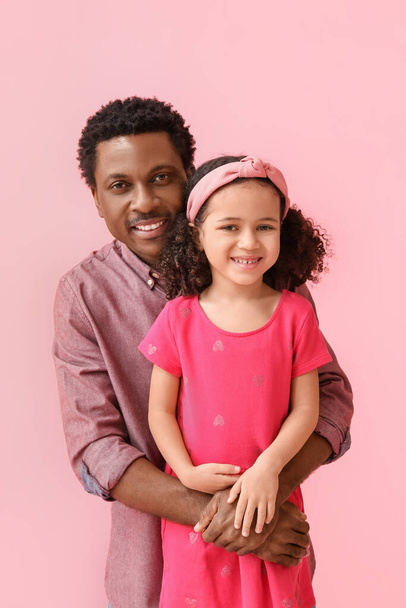 Πορτρέτο του μικρού Αφροαμερικανού κοριτσιού και του πατέρα της σε ροζ φόντο - Φωτογραφία, εικόνα