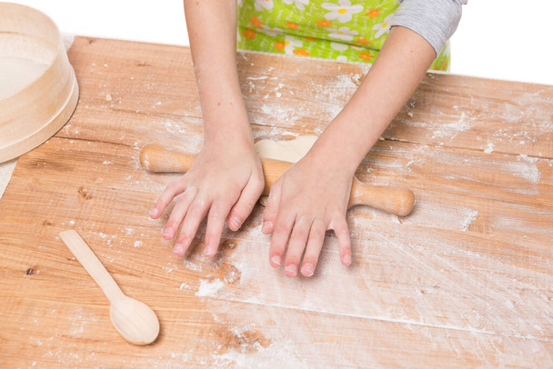 hands of a girl kneading dough and rolling out on a wooden board, close-up of shooting - Photo, Image