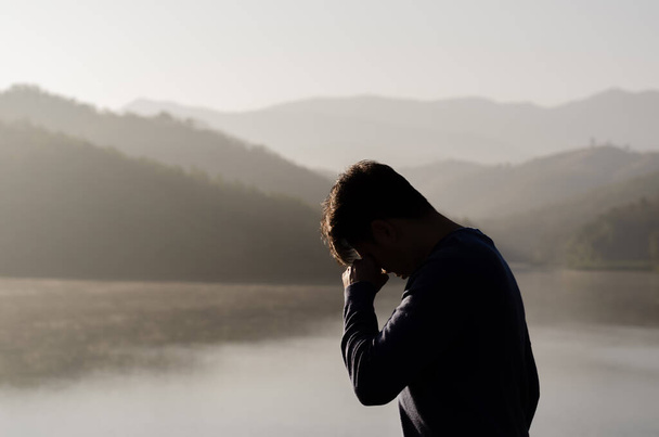 Азиатский жалкий депрессивный человек стоит в одиночестве на фоне гор и озер. Депрессия и психическое здоровье. - Фото, изображение