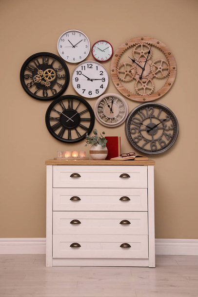 Stylish room interior with collection of wall clocks and dresser - Foto, afbeelding