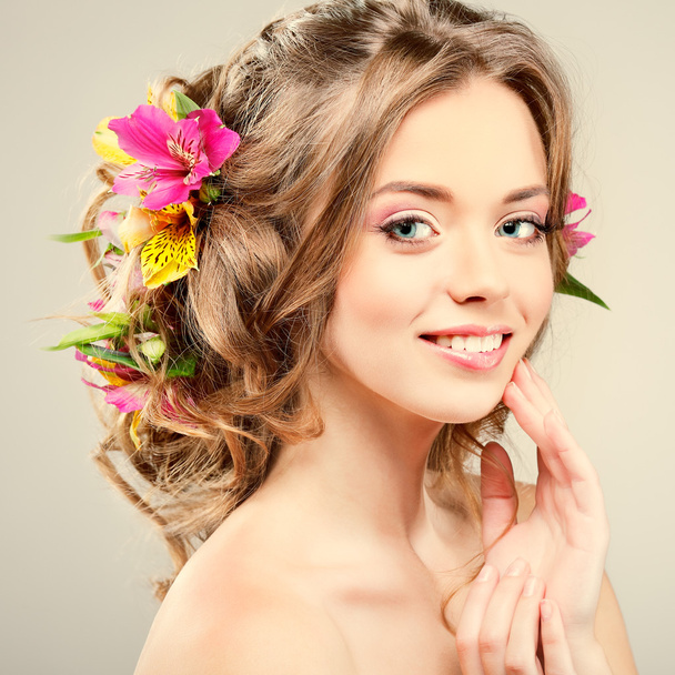 Beautiful  girl, isolated on a light - grey  background with varicoloured flowers  in hairs, emotions, cosmetics - Φωτογραφία, εικόνα