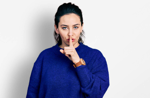 Молода іспаномовна жінка в повсякденному одязі просить мовчати з пальцем на губах. тиша і таємна концепція
.  - Фото, зображення