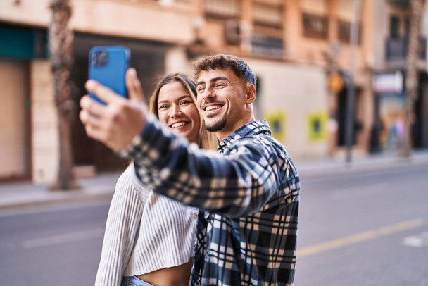 młody mężczyzna i kobieta para uśmiecha się pewnie co selfie przez smartfona na ulicy - Zdjęcie, obraz