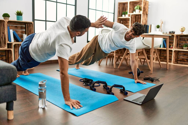 Due uomini ispanici coppia sorridente fiducioso avere on-line abs esercizio classe a casa - Foto, immagini